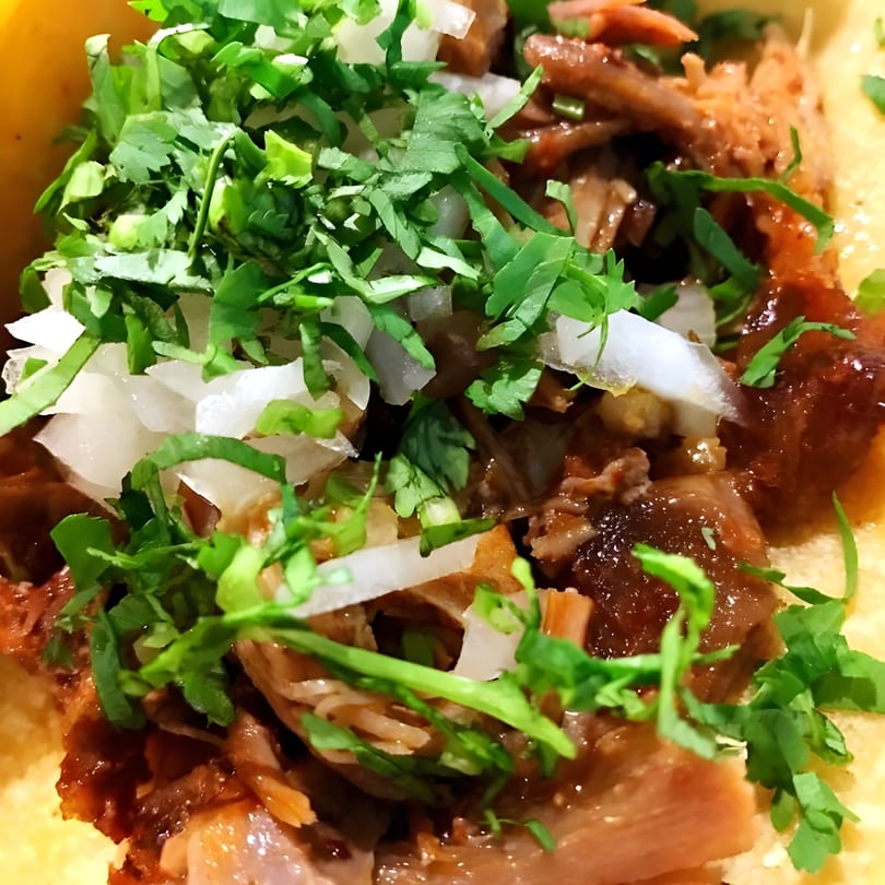 Close-up of a Sol Azteca Mexican taco filled with meat, cilantro, and diced onions.